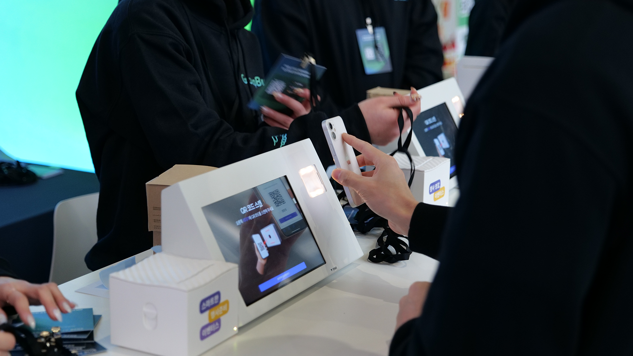 키오스크에서 QR을 스캔해 출석 체크와 명찰 출력을 동시에 완료하는 참가자