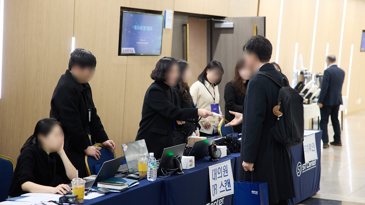 컨퍼런스 등록데스크에서 참가자 확인과 명찰 배부가 진행되는 현장