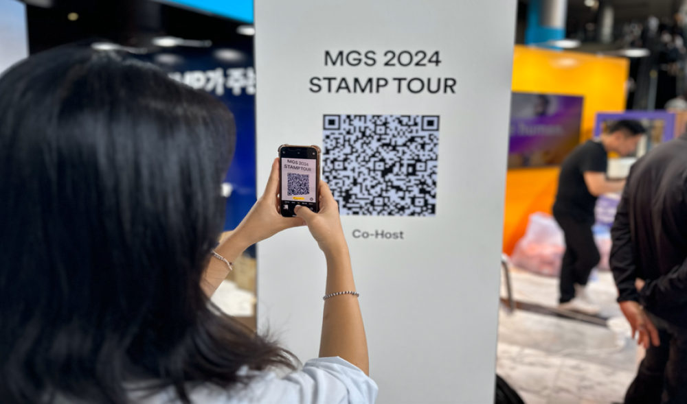참가자가 부스에 설치된 스탬프투어 QR 코드를 스마트폰으로 스캔하는 모습