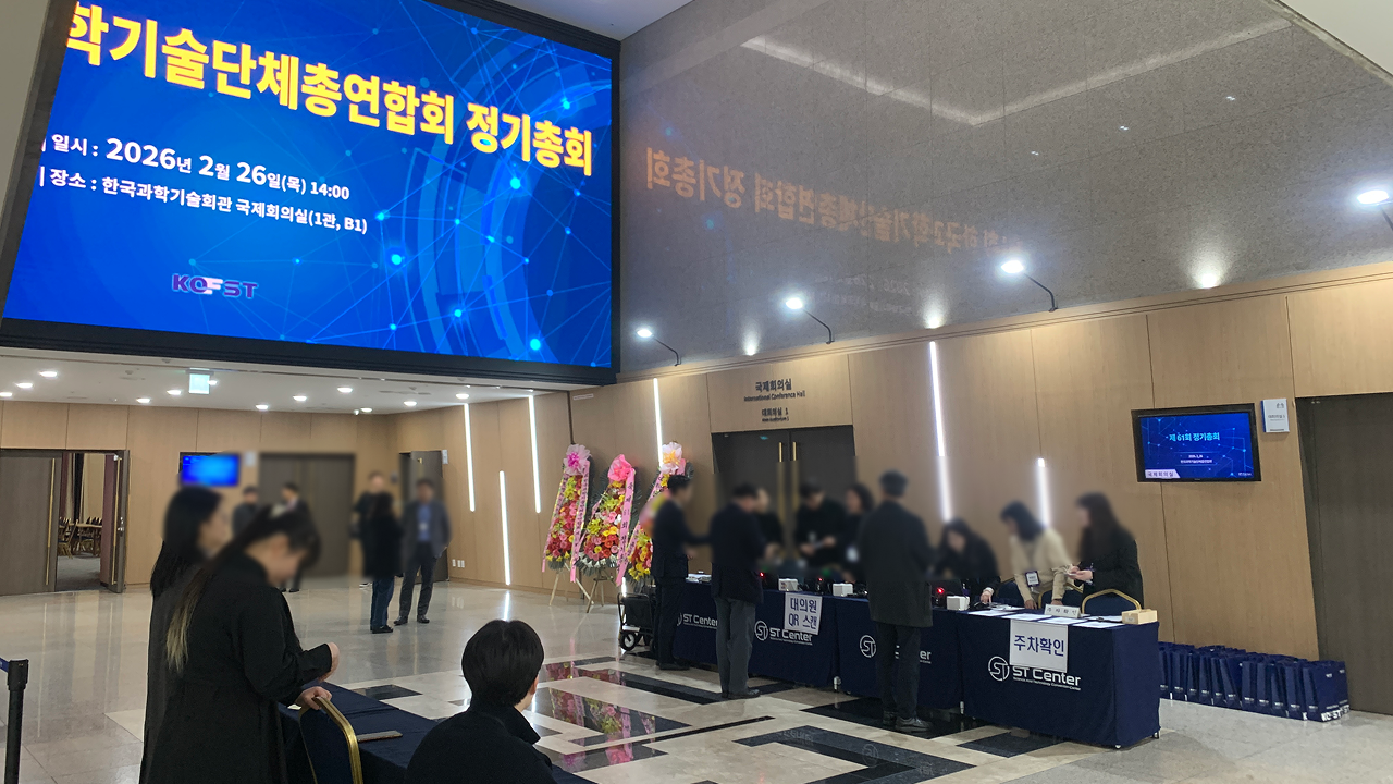 컨퍼런스 행사장 입구에서 참가자 등록과 체크인이 진행되는 모습